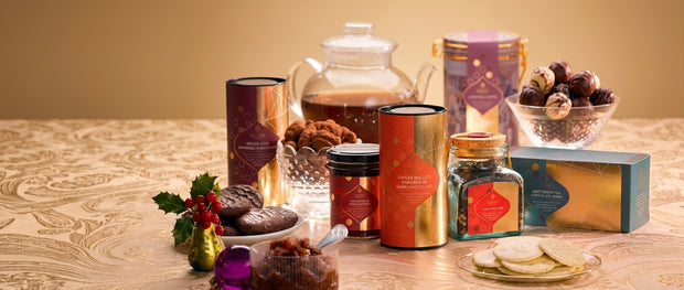 Gourmet food gifts: chocolate-covered biscuits, spiced chai, chutney and tea on a gold cloth