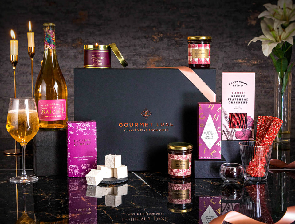 Celebrate with Exclusively Luxe gourmet gift hamper featuring wine, sweets, and elegant snacks.